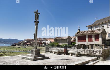 Steinkreuzskulptur und traditionelle galizische Getreidespeicher im Dorf Combarro, Spanien Stockfoto