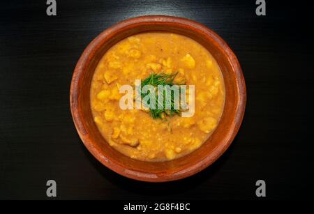 Arabische Küche – schälte Fava-Bohnen in einer weißen Schüssel auf dunkelbraunem Hintergrund. Draufsicht. Foul Mudammas Stockfoto