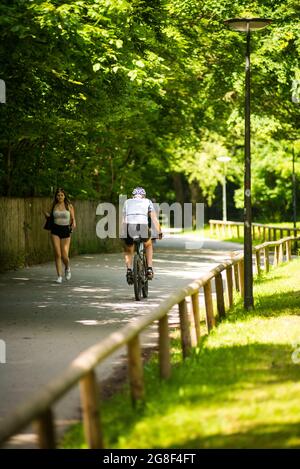 München, Deutschland-Juli 19,2021: Ein Mann fährt mit dem Fahrrad auf einem Weg in einen Park Stockfoto