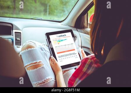 Frau schreibt eine Kundenbewertung und hinterlässt eine Bewertung auf dem Tablet. Kundenerfahrung und Feedback-Konzept. Stockfoto