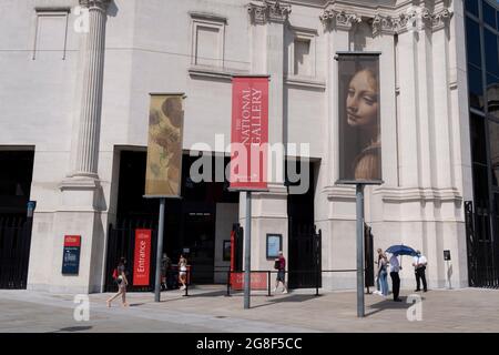 Besucher kommen am Covid „Freedom Day“ am Eingang der National Gallery am Trafalgar Square an. Dieses Datum hat die britische Regierung von Premierminister Boris Johnson als das Ende der strengen, durch Covid pandemischen sozialen Distanzierungsbedingungen mit dem Ende der obligatorischen Gesichtsbedeckungen in Geschäften und öffentlichen Verkehrsmitteln am 19. Juli 2021 in London, England, festgelegt. Die Banner sind für die aktuelle Ausstellung der italienischen Barockkunst von Artemisia Gentileschi bestimmt. Stockfoto