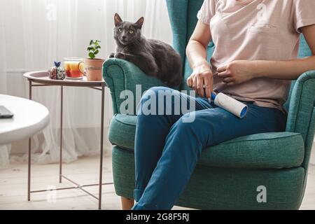 Frau, die Kleidung mit Haftwalze von Katzenhaaren reinigt.Cleanin Stockfoto