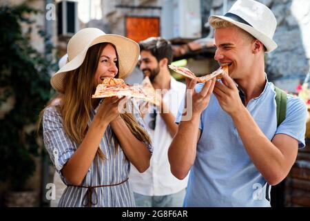 Glückliche Gruppe von Menschen essen Pizza im Freien, sie genießen zusammen. Stockfoto