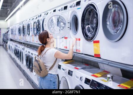 Kaukasische Frau wählt eine Waschmaschine in einem Haushaltswarenladen Stockfoto