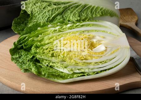 Ganz und halb frischer roher chinesischer Kohl aus der Nähe auf einem Schneidebrett Stockfoto