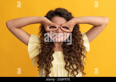 Lustiges Kind mit langen lockigen Haaren und perfekte Haut macht Gesichter, viel Spaß Stockfoto