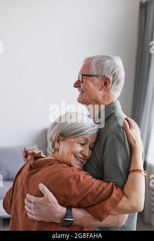Vertikales Porträt eines liebenden älteren Paares, das zu Hause in minimalem Setting zusammen tanzt, Kopierraum Stockfoto