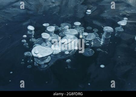Luftblasen, die im Eis gefangen sind, Nahaufnahme, dunkelblauer Hintergrund, Textur, abstrakt Stockfoto