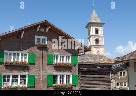 Altes Holzhaus neben dem Kirchturm des Bergdorfes Vrin in der schweiz Stockfoto