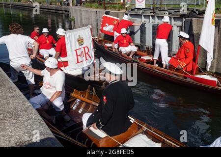 Boveney Lock, in der Nähe von Eton, Großbritannien: 20. Juli 2021. Jährliche Swan Upping Zählung der Schwanenpopulation an der Themse. Swan Uppers von der Worshipful Company of Vintners und der Worshipful Company of Dyers rudern mit dem Schwanenmarker der Königin David Barber (Scharlach-Blazer) in traditionellen Skiffs flussaufwärts. Die jährliche Veranstaltung geht vermutlich auf das Jahr 1189 zurück, als die Krone den Besitz aller stummen Schwäne für Essen für Bankette und Feste beanspruchte. Heute werden die Cygnets gewogen und gemessen, um Schätzungen der Wachstumsraten zu erhalten, und auf Anzeichen von Verletzungen untersucht, die in der Regel durch Angelhaken und Angelschnur verursacht werden. Stockfoto