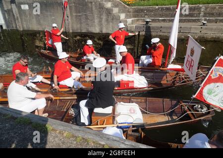 Boveney Lock, in der Nähe von Eton, Großbritannien: 20. Juli 2021. Jährliche Swan Upping Zählung der Schwanenpopulation an der Themse. Swan Uppers von der Worshipful Company of Vintners und der Worshipful Company of Dyers rudern mit dem Schwanenmarker der Königin David Barber (Scharlach-Blazer) in traditionellen Skiffs flussaufwärts. Die jährliche Veranstaltung geht vermutlich auf das Jahr 1189 zurück, als die Krone den Besitz aller stummen Schwäne für Essen für Bankette und Feste beanspruchte. Heute werden die Cygnets gewogen und gemessen, um Schätzungen der Wachstumsraten zu erhalten, und auf Anzeichen von Verletzungen untersucht, die in der Regel durch Angelhaken und Angelschnur verursacht werden. Stockfoto