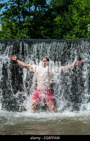 Ein Mann kühlt sich im Wasser von Warleigh Weir am Fluss Avon in der Nähe von Bath in Somerset ab, während die Temperaturen über das Vereinigte Königreich steigen Stockfoto