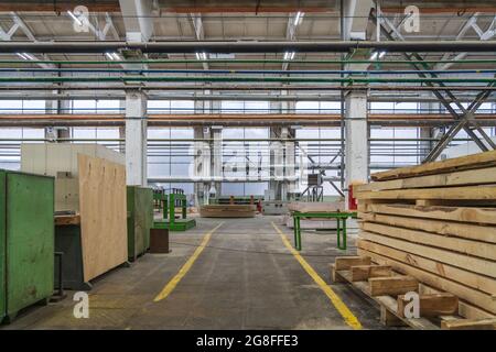 Typische Holzbearbeitungswerkstätten, große Werkstatt mit automatisierten Maschinen und Holzstapeln. Stockfoto