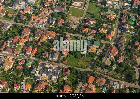 Wohngebiet, Dächer, Blick von einer Drohne. Ferienhäuser im Dorf. Blick auf das Land durch das Flugzeugfenster. . Schauen Sie aus dem Fenster eines fliegenden Flugzeugs Stockfoto