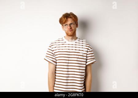 Trauriger und düsterer Rotschopf-Mann, der oben links in die Ecke schaut, schmollend und sich wie Verlierer anfühlt und über weißem Hintergrund steht Stockfoto
