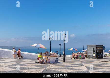 Nazare, Portugal - 28. Juni 2021: Frau in traditioneller Kleidung, die getrocknete Früchte auf dem Miradouro do Suberco verkauft Stockfoto