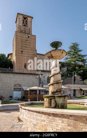 Vertikale Ansicht des Brunnens auf der Piazzale San Francesco im historischen Zentrum von Cascia, Italien, mit der gleichnamigen Kirche im Hintergrund Stockfoto