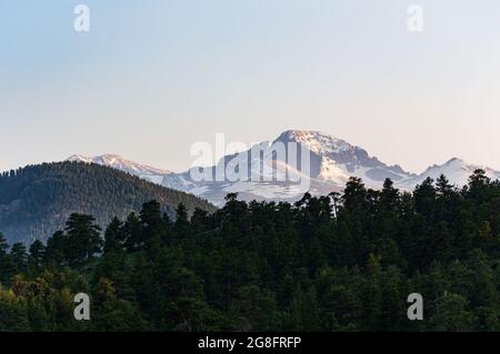 Berglandschaft Blick auf Long's Peak bei Sonnenuntergang mit dunklem Baumwald im Vordergrund und dramatischer Beleuchtung Stockfoto