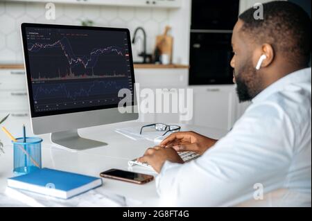 Investitionen, Handel an der Börse. afroamerikanischer Mann-Händler-Investor, analysiert Kryptowährung-Finanzmarkt, schaut auf Computer, Trading-Daten-Index-Chart-Grafik auf pc-Bildschirm Stockfoto