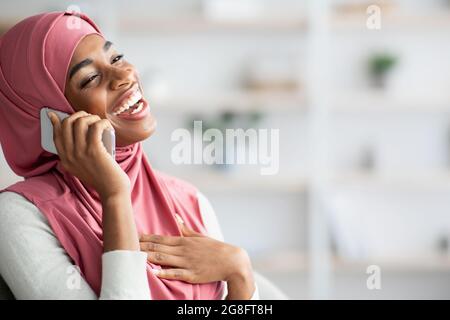 Mobile Anrufe. Fröhliche Schwarze Muslimische Dame In Hijab Nimmt Auf Handy Stockfoto