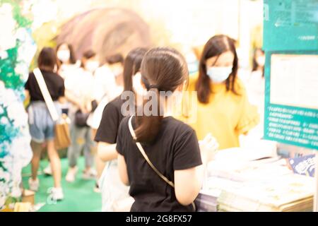 Menschen mit Gesichtsmasken lesen und kaufen Bücher auf der Hong Kong Book Fair im Hong Kong Convention and Exhibition Centre, Wan Chai während der Covid-19 Stockfoto