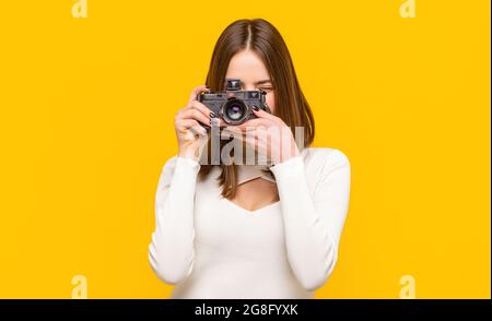 Fotograf Kamera Foto, Fotografieren Mädchen Freude machen Fotografie unter Konzept. Mädchen mit einer Kamera. Frau, die die Kamera auf gelben Hintergrund hält Stockfoto