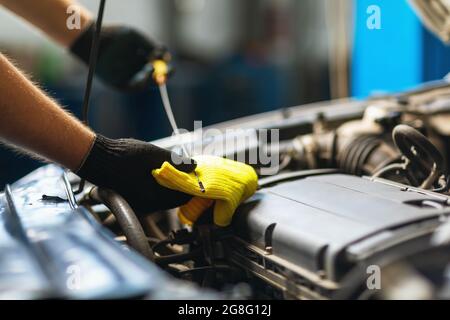 Ein Automechaniker überprüft den Ölstand in einem Automotor mit einem speziellen Messstab Stockfoto