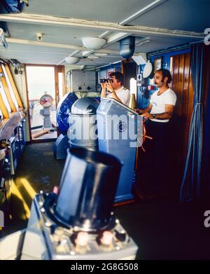 Innendeck des Kreuzschiffs, Steuermann-Steuerung, Kapitän schaut durch Ferngläser, Saronischer Golf, Ägäisches Meer, Griechenland, Europa, Stockfoto