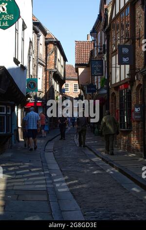 Menschen, die entlang einer engen historischen Einkaufsstraße mit Fachwerkhäusern und unabhängigen Geschäften spazieren, England. Stockfoto