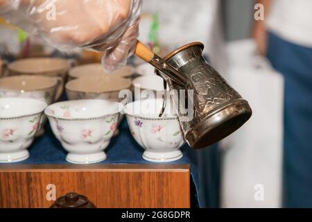 Kupfercezve mit türkischem Kaffee, der ausgießt. Orientalischer Kaffee. Stockfoto