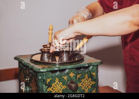 Frau macht türkischen Kaffee auf einer Kaffeemaschine mit Sand in CEZVE. Orientalischer Kaffee. Stockfoto
