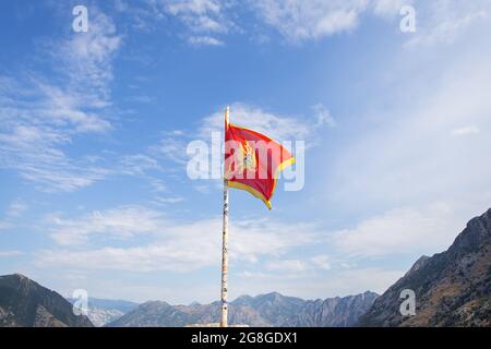 Montenegro Flagge vor dem Hintergrund eines schönen blauen Himmels mit Wolken flattern im Wind Stockfoto