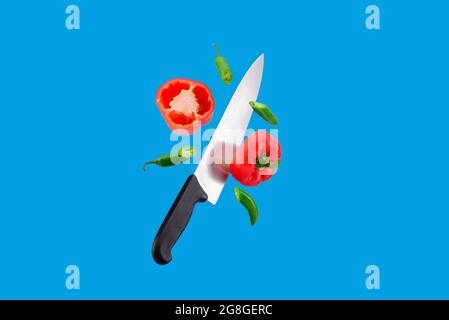 Floating Knife schneidet mexikanische Chilischoten, rote Chilischoten und grüne serrano-Chilischoten auf einem blauen Hintergrund Stockfoto