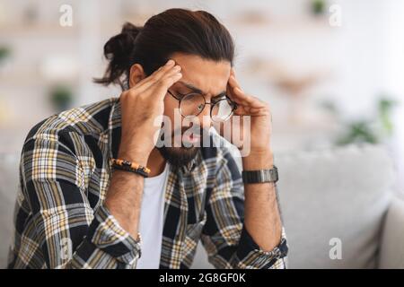 Nahaufnahme eines traurigen arabischen Mannes, der seinen Kopf berührt Stockfoto