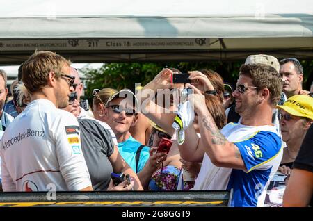 Jenson Button posiert mit Fans für Fotos, bevor er sich auf das Rennen eines klassischen McLaren-Rennwagens beim Goodwood Festival of Speed in Großbritannien vorbereitete Stockfoto