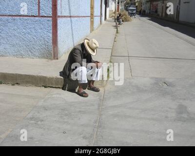 Celendin, Peru. Ein alter peruanischer Mann, der einen Sombrero trägt und allein an der Straßenecke in der Andenstadt Celendin sitzt. Juli 2010 Stockfoto