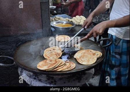 Lachcha-Parathen werden mit Hitze in Bratpfanne zubereitet, am Abend zum Verkauf als Street Food in Kalkutta, Indien. Indien ist berühmt für seine würzigen indischen Vegen Stockfoto