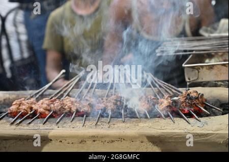 Hähnchen Seekh Kababs werden mit Hitze in Grill mit Metallspießen gegrillt, am Abend zum Verkauf als Street Food in Kalkutta, Indien. Indien ist berühmt Stockfoto