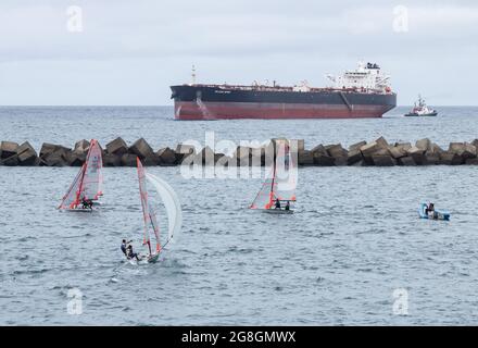 Kleines Segelschiff in der Nähe von Bohrschiffen. Stockfoto