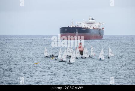 Kleines Segelschiff in der Nähe von Bohrschiffen. Stockfoto