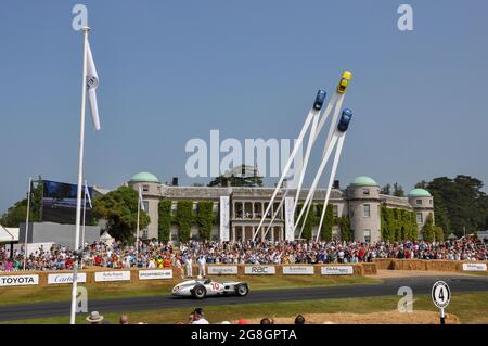 Stirling Moss fährt beim Goodwood Festival of Speed mit dem historischen Mercedes Benz W196, vorbei am Goodwood House und dem Porsche-Hauptmerkmal Stockfoto