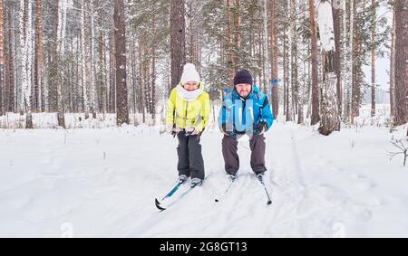 Ein glückliches Seniorenpaar fährt im verschneiten Wald Skilanglauf Stockfoto