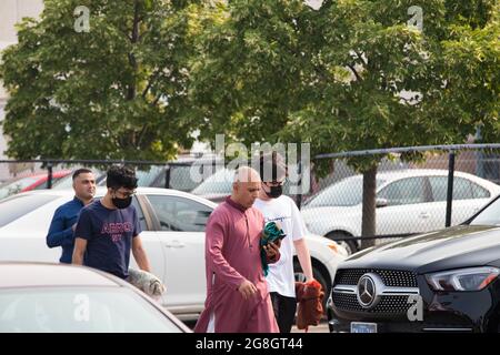 Einige muslimische Männer gehen zusammen mit ihren Gebetsteppichen während des Eid-Festes durch den Parkplatz. Stockfoto