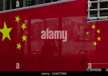 Hongkong, China. 30. Juni 2021. Eine Reflektion eines Mannes durch eine chinesische Flagge während des Jahrestages. Trotz der COVID-19 Pandemie, Und Chinas nationales Sicherheitsgesetz, das gegen die demokratische Bewegung Hongkongs vorgeht, wurden zahlreiche chinesische Propagandas in der ganzen Stadt festgehalten und gesehen, während die Kommunistische Partei Chinas ihren 100. Jahrestag und Hongkongs Umsatz nach 24 Jahren feiert. (Foto von Alex Chan Tsz Yuk/SOPA Images/Sipa USA) Quelle: SIPA USA/Alamy Live News Stockfoto