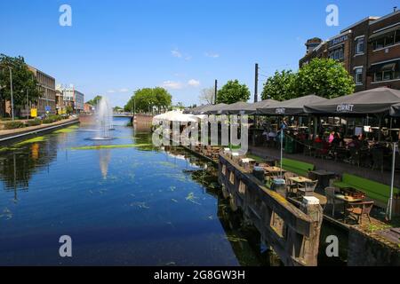 Helmond, Niederlande - Juli 10. 2021: Blick auf den holländischen Wasserkanal mit Brunnen, Bars und Restaurants, Menschen, die draußen im Schatten unter Sonnenschirmen sitzen i Stockfoto