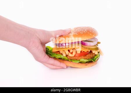 Hand greifen einen großen Chicken Burger mit Käse und Gemüse Stockfoto