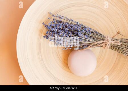 Handgemachte Lavendelseife. Stück natürliche Seife in Kugelform mit getrockneten Lavendelblüten auf einem Holzteller. Bio-Kosmetik für Hautpflege und Spa. Stockfoto