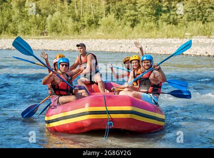 Gruppe von Touristen, die mit dem starken Strom des Gebirgsflusses kämpfen. Stockfoto