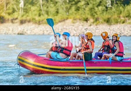 Gruppe von Touristen, die mit dem starken Strom des Gebirgsflusses kämpfen. Stockfoto