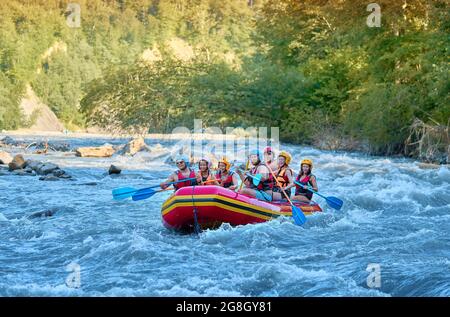 Gruppe von Touristen, die mit dem starken Strom des Gebirgsflusses kämpfen. Stockfoto